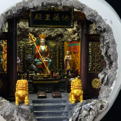 Close-up interior view of the 地藏王殿 miniature shrine diorama featuring Ksitigarbha Bodhisattva seated on a throne holding a golden ringed staff, flanked by two attendant figurines and two gold Kirin guardians on the altar steps, with dark carved wooden panels and the 地藏王殿 plaque above the entrance