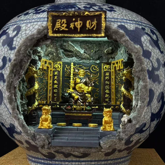 A close-up of a vase with a large broken-front opening, revealing a Wu Caishen miniature golden temple scene inside. The vase is white with blue crackled glaze patterning, and the interior features gold figurines, black panels, dragon motifs, and a central plaque with Chinese characters.