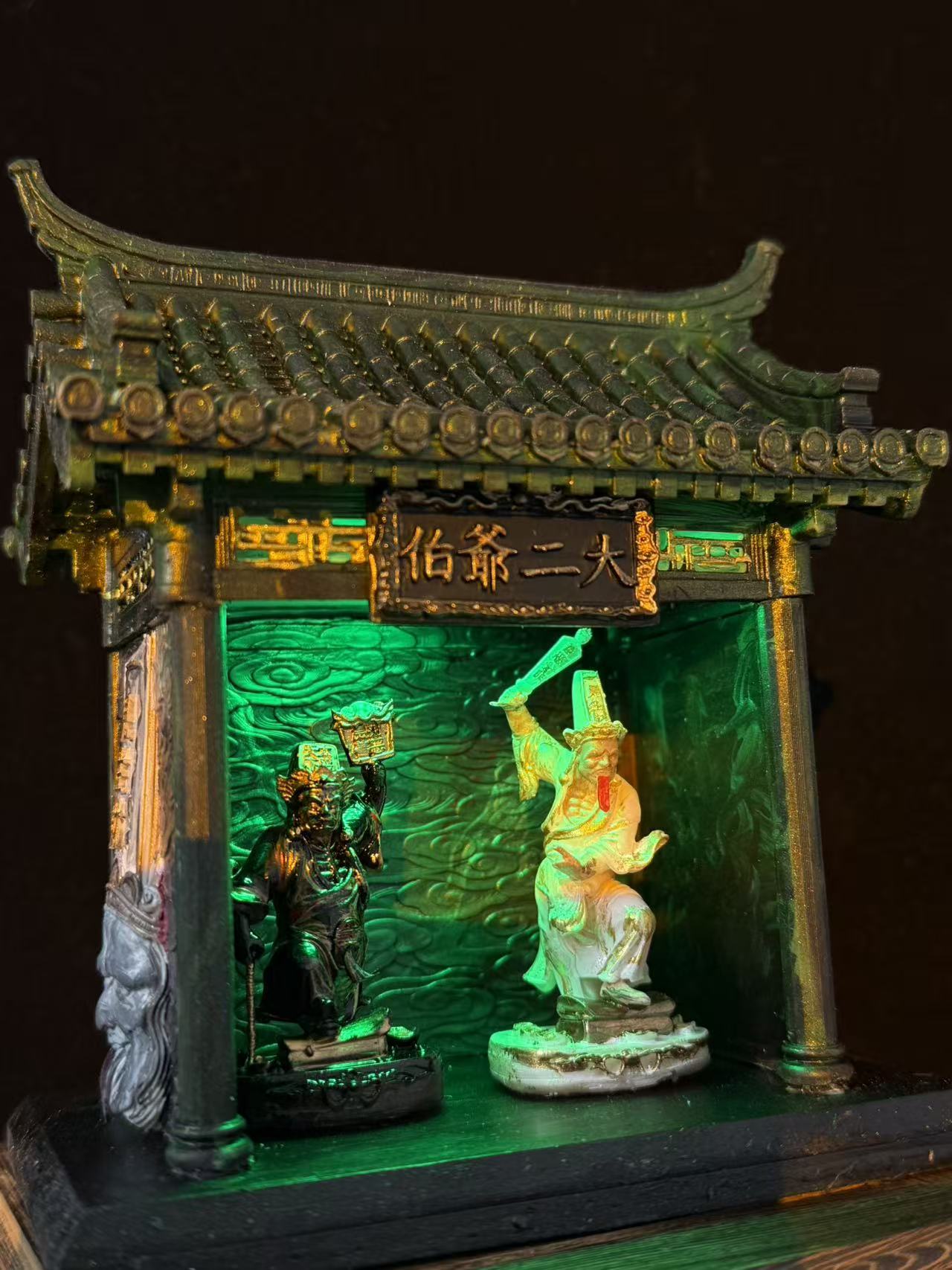 Side angle view of a miniature car shrine temple model featuring Tua Di Ya Pek, showing depth and green-lit interior