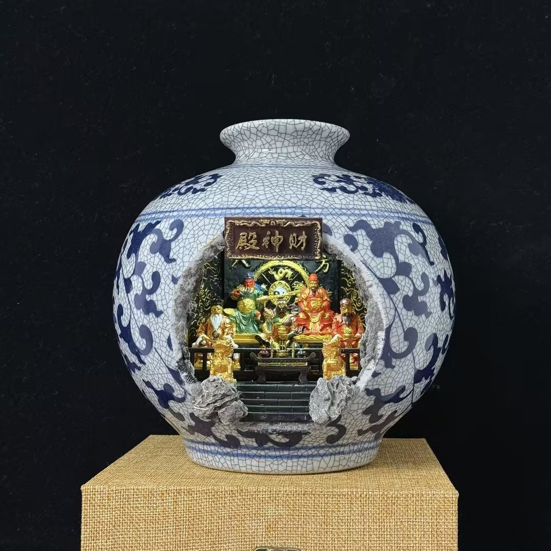 Blue and white crackle-glaze porcelain vase with a cave cutout revealing an illuminated Five Roads God of Wealth shrine diorama (财神殿) inside, displayed on a burlap mat against a black background