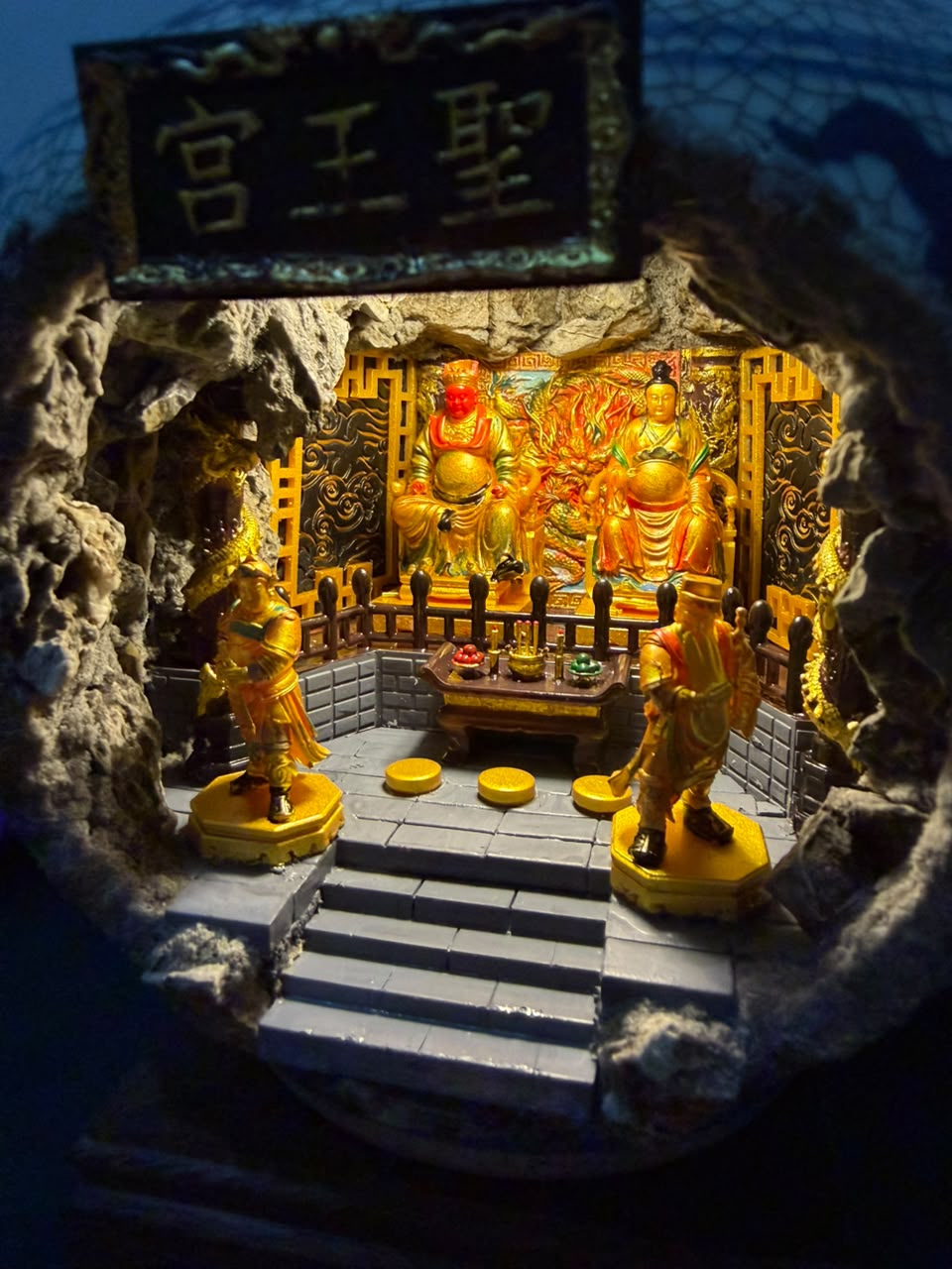 Interior view of the 圣王宫 shrine diorama seen through the cave opening of the porcelain vase, featuring Guangze Zunwang and Miao Yin Xian Zi under deep blue ambient lighting with two gold attendant figurines in the foreground