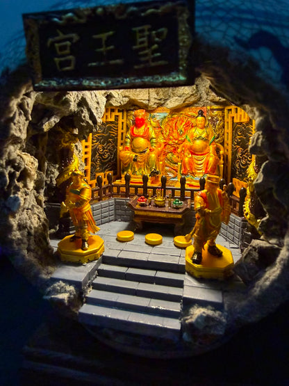 Interior view of the 圣王宫 shrine diorama seen through the cave opening of the porcelain vase, featuring Guangze Zunwang and Miao Yin Xian Zi under deep blue ambient lighting with two gold attendant figurines in the foreground